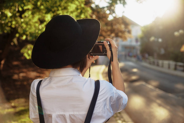 Девушка в черной шляпе стреляет в старом европейском городе. - Фото, изображение