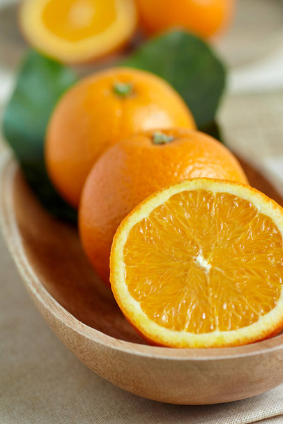 Narancs egy fa tálban levelekkel - Fotó, kép