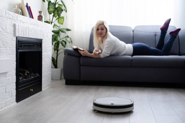 people, housework and technology concept - happy woman and robot vacuum cleaner at home - Foto, immagini