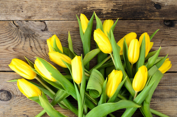 Żółte tulipany leżą na starej drewnianej powierzchni. Studio zdjęcie - Zdjęcie, obraz