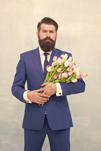 Bearded man with tulip bouquet. Love date. Womens day. March 8. Spring gift. Bearded man hipster with flowers. Celebrate spring. Making surprise. Gentleman with tulips. Spring is coming. Greetings - Photo, Image
