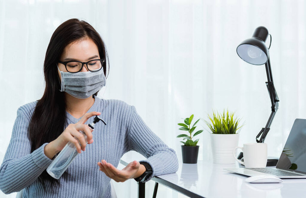 Asian young business beautiful woman wearing face mask protective working from home office with laptop computer desk he quarantines disease coronavirus and cleaning hands by sanitizer alcohol gel pump - Photo, Image