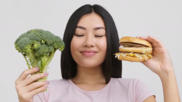 aziatische vrouw houden hamer en broccoli kiezen voedsel, witte achtergrond - Video