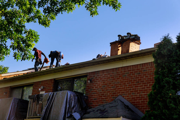 Будівельник на ремонтному даху будинку встановив нову черепицю
 - Фото, зображення