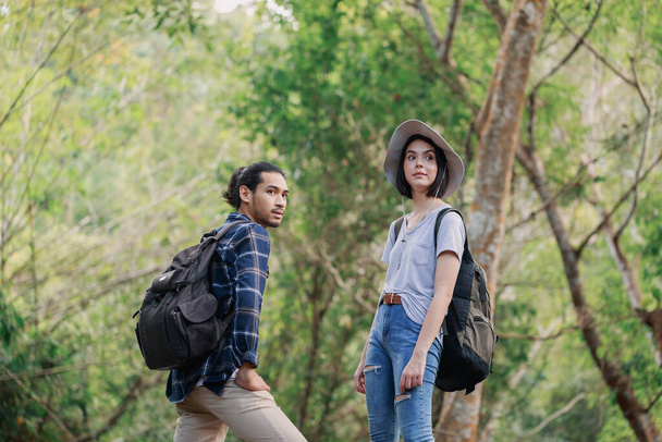 Ormanda yürüyüş yapan mutlu bir çift. Aktif genç Kafkas kadın yürüyüşçü ve Asyalı erkek. - Fotoğraf, Görsel