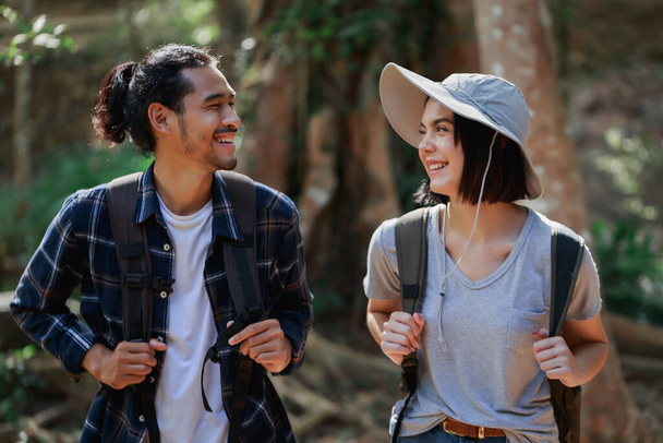 Szczęśliwa para spacerująca po lesie. Aktywny młody biały kobieta turysta i Azji mężczyzna. - Zdjęcie, obraz