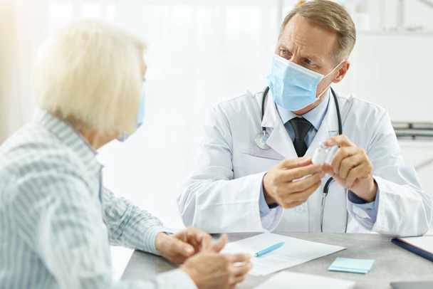 Médico masculino em máscara médica discutindo vacina com paciente - Foto, Imagem
