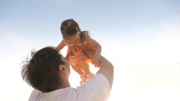Babam sağlıklı mutlu kızını kollarında mavi gökyüzüne kaldırdı. Baba ve küçük çocuk dışarıda birlikte oynuyorlar. Aile oyunları. Parktaki bebek ve baba. Babaların izin günü. Mutlu aile ve çocukluk - Video, Çekim