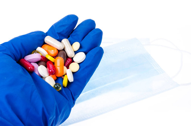 Рука в медичній рукавичці тримає кольорові таблетки, таблетки і капсули. Студія Фото
 - Фото, зображення