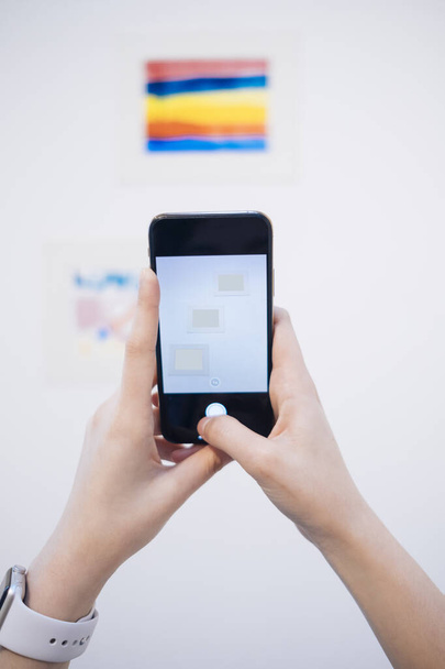 Kéz a nő gazdaság okostelefon fénykép alkotás fehér galériában. - Fotó, kép