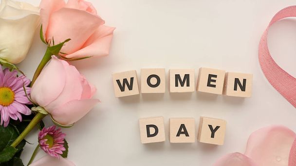 Dice with word "Women day" on white table background decorated with pink flowers and ribbon - Photo, Image