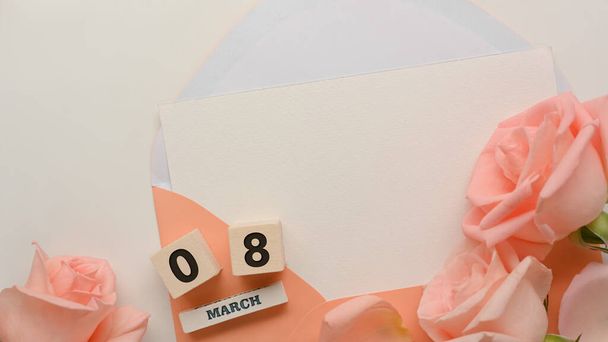 Mock up card in pastel envelope in Women's day concept on white table background with pink flowers  - Φωτογραφία, εικόνα