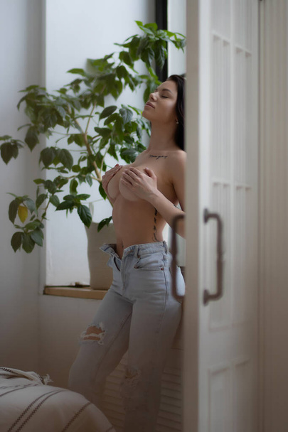 Crop beautiful slim sexual nude woman in underwear closing breast and posing in room - Photo, Image
