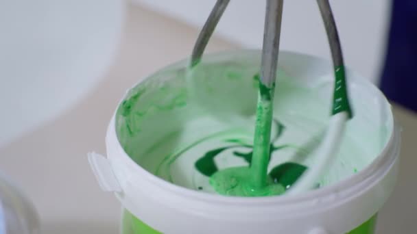 costruttore mescola vernice bianca e verde in secchio per dipingere pareti all'interno durante la ristrutturazione - Filmati, video