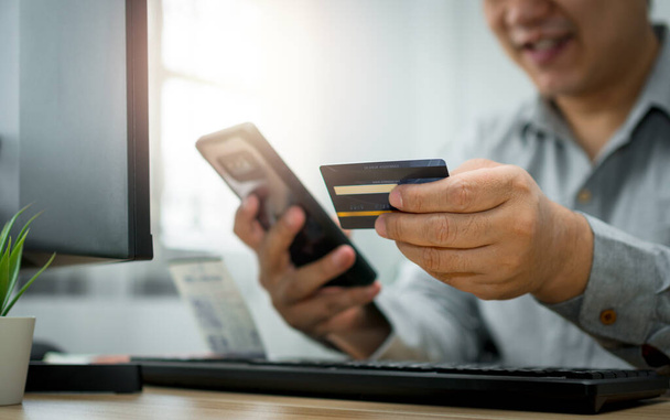 Mies, jolla on luottokortti ja joka käyttää älypuhelinta maksamiseen verkossa ostettaessa tilaustuotteita internetin kautta. Sähköisen kaupankäynnin teknologian käsite (sähköinen kaupankäynti) - Valokuva, kuva