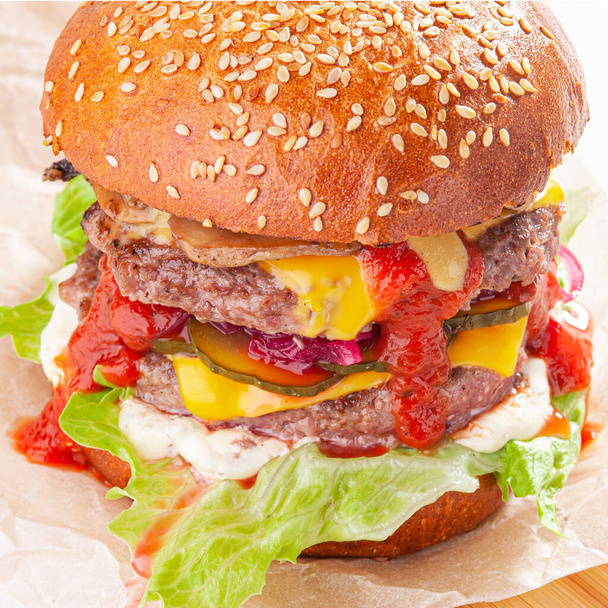 Peynirli, domatesli, marullu, mantarlı ve ketçaplı duble Amerikan sığır burger. - Fotoğraf, Görsel