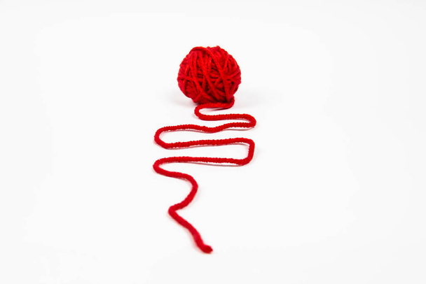 Κόκκινο κουβάρι κλωστής σε λευκό φόντο. Κόκκινη μπάλα από μαλλί κόκκινο νήμα απομονωμένο σε λευκό - Φωτογραφία, εικόνα