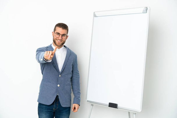 Νεαρή επιχειρηματίας δίνει μια παρουσίαση σε λευκό πίνακα απομονώνονται σε λευκό φόντο δείχνει και να άρει ένα δάχτυλο - Φωτογραφία, εικόνα