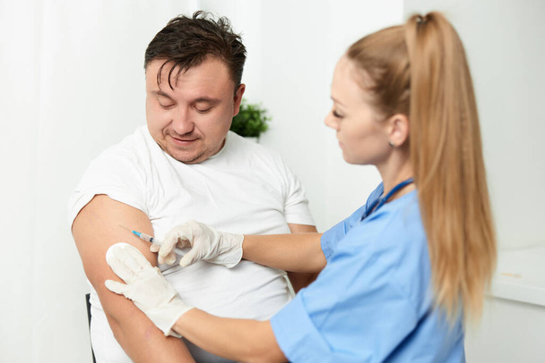 female doctor injects the vaccine into the arm of a male patient - Photo, Image