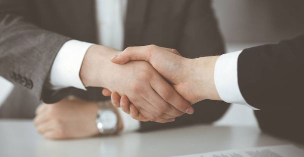 Unknown businessman shaking hands with his colleague or partner above the glass desk in modern office, close-up. Business people group at meeting - Foto, immagini