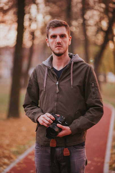 BRCKO, BOSNIA AND HERZEGOVINA - Oct 23, 2018: Man holding Canon camera in park - Foto, Imagen
