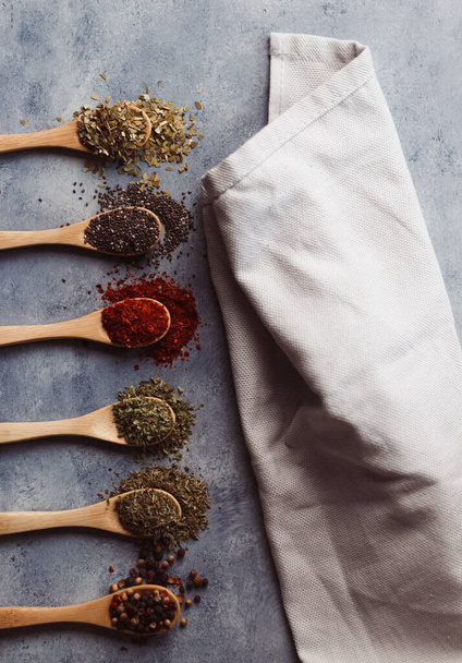 A vertical shot of a towel and assortment of spices: chia, paprika, parsley, rosemary, and teas - Fotó, kép