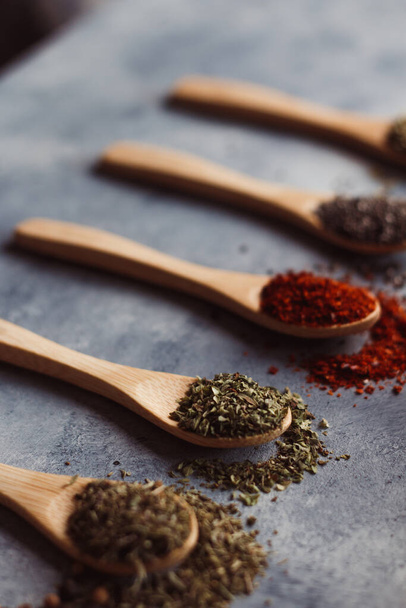 A vertical shot of assortment of spiceson wooden spoons: chia, paprika, parsley, rosemary, and teas - Fotoğraf, Görsel