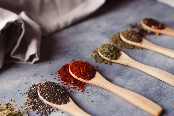 A selective focus shot of assortment of spices: chia, paprika, parsley, rosemary, and teas - Фото, изображение