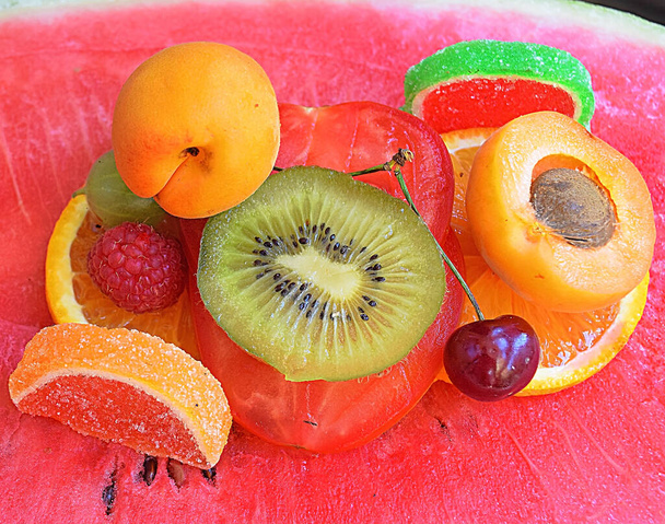 композиція зі свіжих фруктів з зацукрованим фруктовим желе з помідорами на темному фоні, вид зверху
  - Фото, зображення