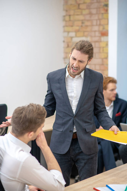 Nervous man with documents shouting at employee - Photo, Image