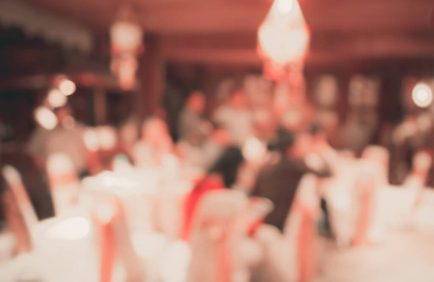 Imagen borrosa abstracta de Conjunto de mesa de comedor grande para bodas, cenas o eventos de festivales con hermosa decoración de luces dentro de un gran salón para uso de fondo. (tono vintage) - Foto, imagen