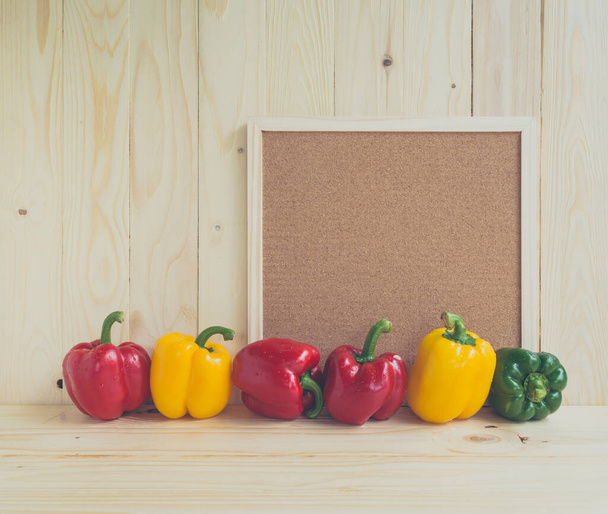 Vintage tone image of sweet peppers on wooden table and wood board for background. - Фото, изображение