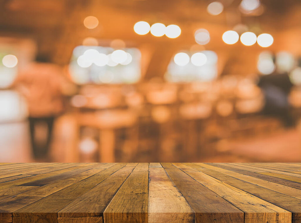 vintage tone wood table and  blur image of coffee shop or restaurant with bokeh on day time for background usage. - Foto, Bild