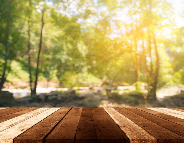 wood table and blur image of Abstract Bokeh of green tree with sun for background usage.(vintage tone) - 写真・画像