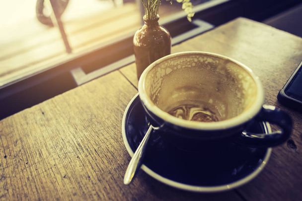 вінтажний тон зображення порожньої чашки лате кави, що залишилася на дерев'яному столі
. - Фото, зображення