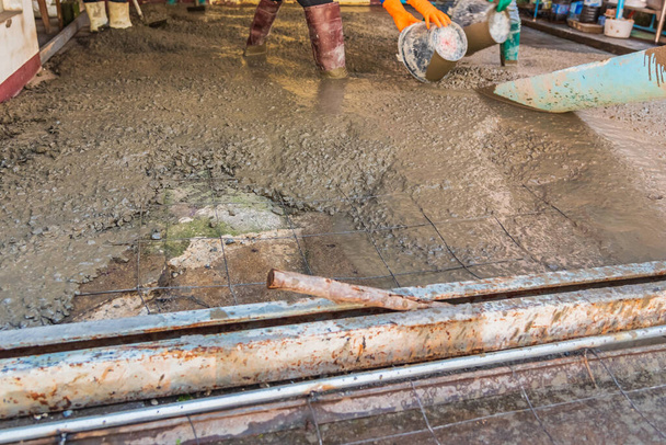 immagine del lavoratore che versa calcestruzzo sul terreno nell'area di costruzione. - Foto, immagini