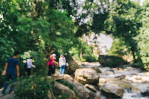 Abstract blur image of people walking in green garden near river from high waterfall with bokeh for background usage. (винтажный тон)) - Фото, изображение