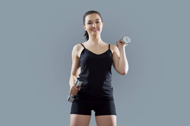 Urheilullinen lihaksikas nuori nainen tekee liikuntaa käsipainoilla - Valokuva, kuva