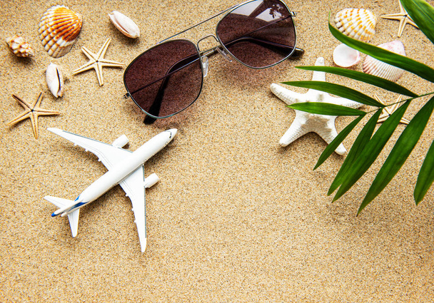 Top view of traveler background on tropical sand, shells and airplane. Background for summer holiday vacation travel trip. Flat lay, copy space - Photo, Image