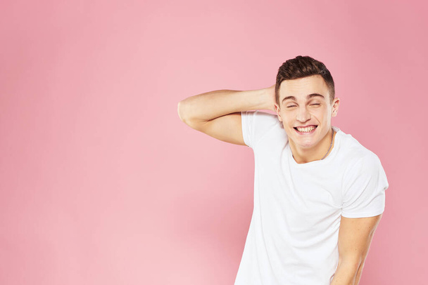 Emotional man gesturing with his hands white t-shirt pink isolated background - Фото, зображення