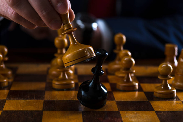 concept of strategy and business planning, businessman behind a chessboard white queen beats a black chess piece, strategy and tactics, readiness for battle, start of battle - Foto, immagini