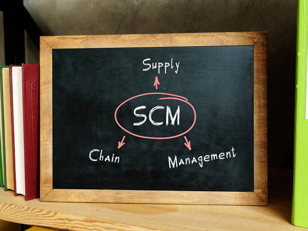  SCM Supply Chain Management felirat. Könyvespolc többszínű könyvekkel és kalkulátokkal - Fotó, kép