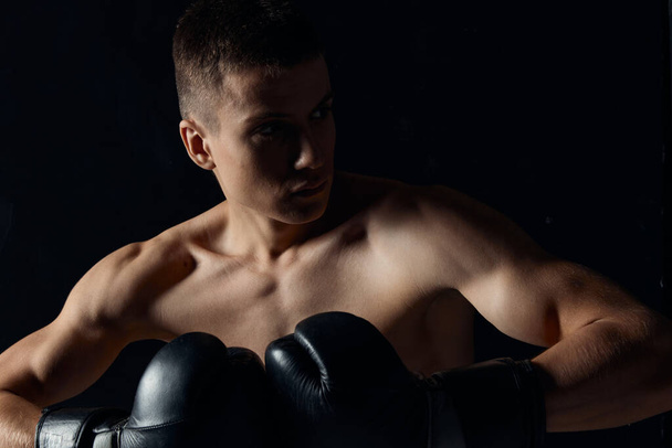 sport guy in boxing gloves close-up portrait black background cropped view - Foto, Imagem