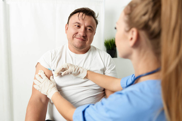 mujer médico inyecciones en el hombro de un hombre paciente cuidado de la salud vacunación covid - Foto, Imagen