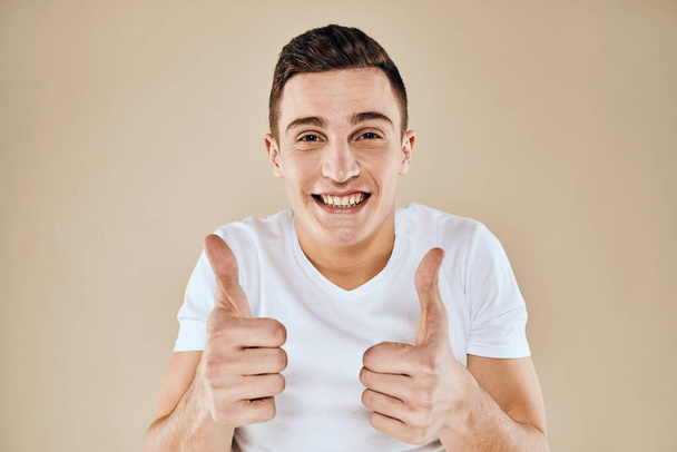 Cute emotional man white t-shirt gesture with hands cropped view beige studio background - Photo, Image