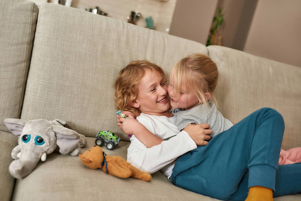 Love you brother. Cute little children, boy and girl cuddling on the sofa at home, showing love and care - Fotoğraf, Görsel