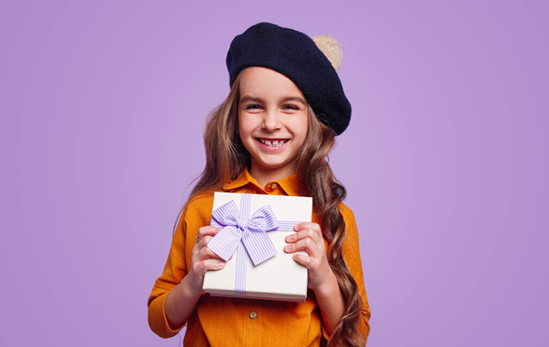 Delighted girl in hat showing gift box - Valokuva, kuva
