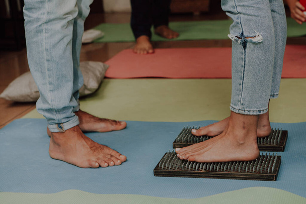Groepspraktijk om op nagels te staan. Close-up van yoga persoon staan op sadhu bord met scherpe nagels. Sadhu houten plank met spijkers voor sadhu training. - Foto, afbeelding