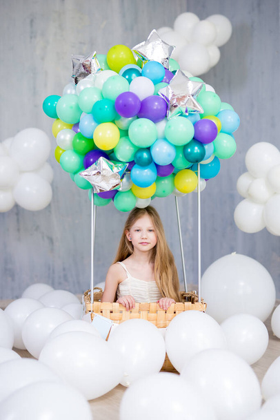 childhood, dream and creativity concept - happy beautiful girl sitting in air balloon basket - Photo, Image