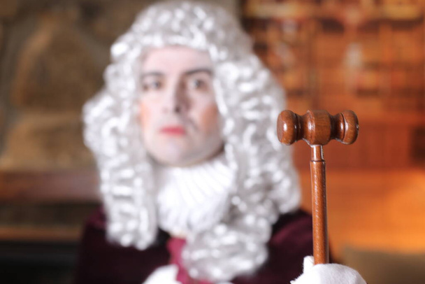 Молодий чоловік у вікторіанському костюмі тримає молоток судді. - Фото, зображення